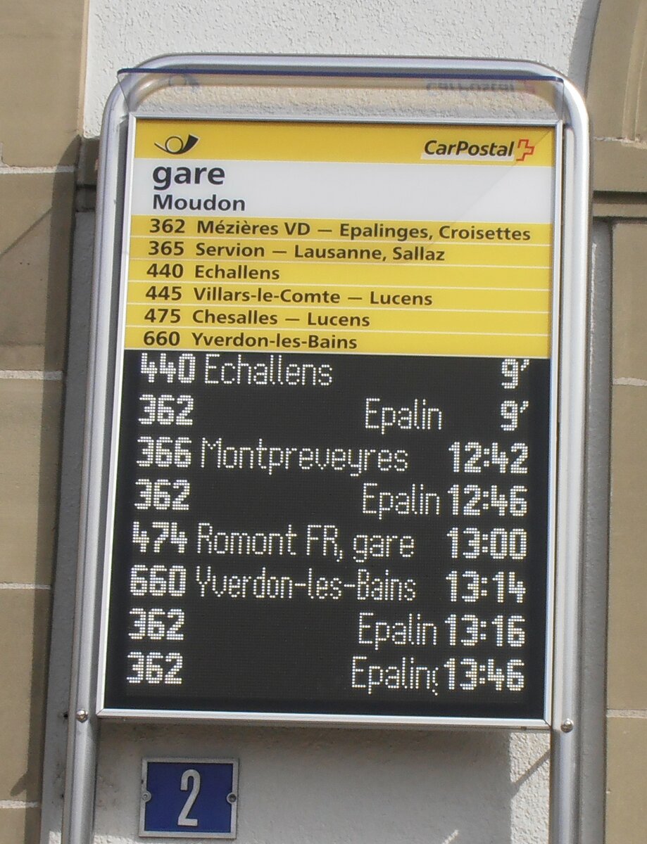 (233'910) - PostAuto-Haltestellenschild und Infobildschirm am 13. Mrz 2022 beim Bahnhof Moudon