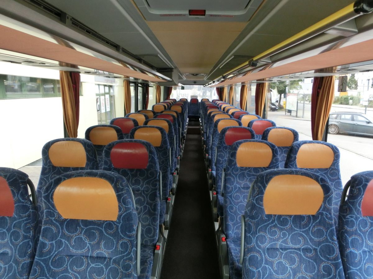 Innenraum des Setra S 315 UL-GT von Josef Kalb aus Norlaching bei Dorfen.
Verbaut sind hier 51 Fahrgastsitze plus 2 Reiseleiterplätze. Die Fahrgastsitze sind Schlafsessel vom Modell Setra 'Top', die über Kurbelarmlehnen, Gurte, Fußrasten und Lederkopfteile verfügen und auf den 330 mm hohen Podesten montiert sind. Auch der Mittelgang ist in diesem Fahrzeug erhöht, sodass sich der gesamte Innenboden auf dem Niveau der H/GT-Modelle befindet. Zur weiteren Innenausstattung gehören die Reisebus-Innenbeleuchtung, Deckensets mit Lüftungsdüsen und Leselampen, Vorhänge und eine TV-Anlage mit DVD-Laufwerk und zwei Monitoren.