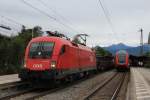 1116 199-1 muss mit einem Stahlzug im Bahnhof von Prien am Chiemsee auf ein freies Gleis warten.